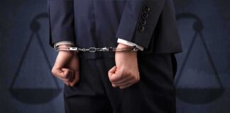 Businessperson in handcuffs with hands behind back