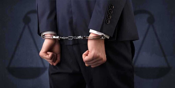Businessperson in handcuffs with hands behind back