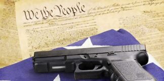 Handgun on American flag with ammunition and U.S. Constitution background