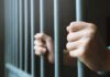 Baby Killer Demands Taxpayer Gender Perks hands gripping prison bars