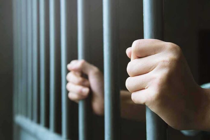 hands gripping prison bars
