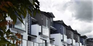 Modern townhouse row with glass balconies and metal accents under cloudy sky