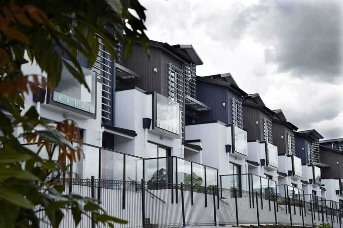 shutterstock_1234800748 Modern townhouse row with glass balconies and metal accents under cloudy sky