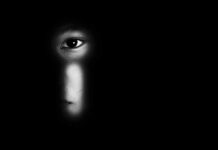 Child Exploitation Ring Tied To Ocean Liners face peering through a keyhole in darkness
