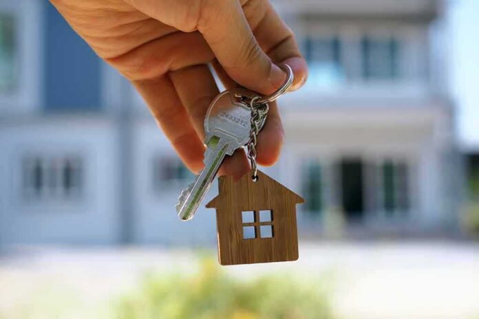 shutterstock_1415127329 Hand holding house keys with a wooden house keychain