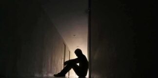 Silhouette of a person sitting on the floor in a dim hallway