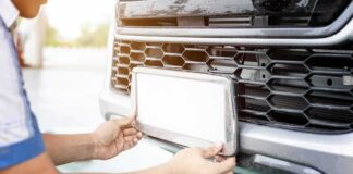 Person installing a car license plate on a front bumper
