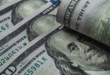 U.S. 100-dollar bills with one note rolled over Benjamin Franklin portrait