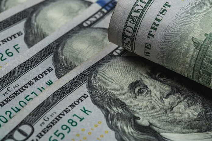 shutterstock_1630138765 U.S. 100-dollar bills with one note rolled over Benjamin Franklin portrait