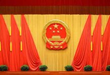 Chinese national emblem on red-draped stage backdrop