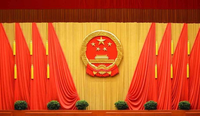 shutterstock_1697991220-2 Chinese national emblem on red-draped stage backdrop