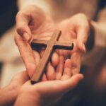 Laywoman Climbs Church Power Ladder Hands holding a wooden cross