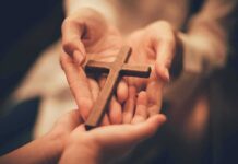 Hands holding a wooden cross