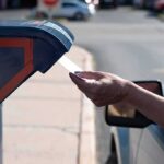 Hand mailing an envelope into a blue mailbox