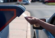 Hand mailing an envelope into a blue mailbox