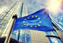 European Union flag waving in front of modern glass office buildings