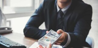 Businessperson hands over a stack of US dollars across a desk