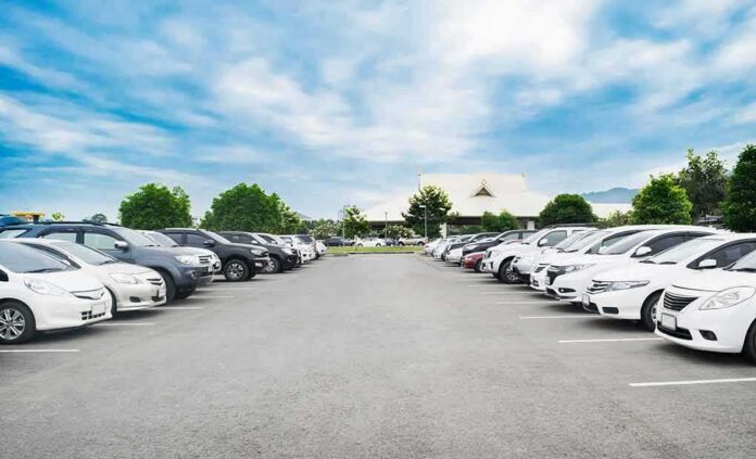 Parking lot lined with cars under a blue sky