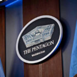 War Powers Showdown – Impeachment Blitz Targets Defense Chief The Pentagon emblem between two flags.