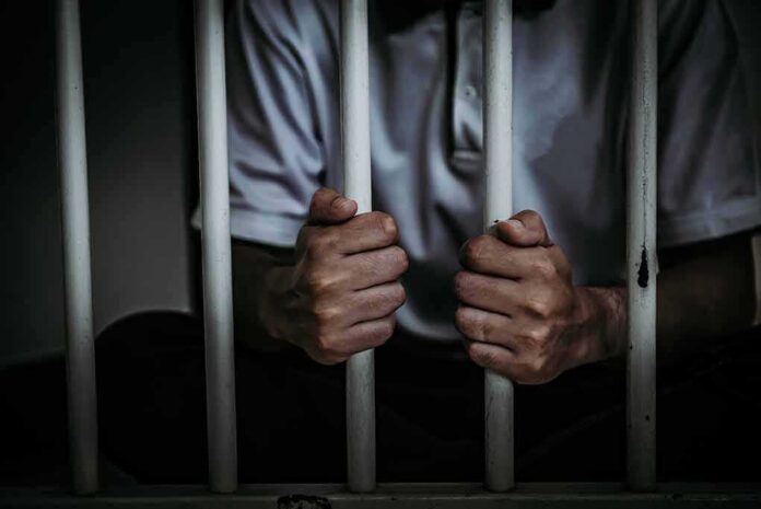 shutterstock_1012787206 person gripping prison bars