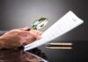 State AG Pounces: Big Tech Immunity Fantasy COLLAPSES Hands holding magnifying glass over contract document
