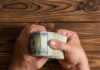 Immigrant Aid Crackdown? NYC Strikes Back Hands holding a thick stack of U.S. hundred-dollar bills