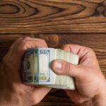 Immigrant Aid Crackdown? NYC Strikes Back Hands holding a thick stack of U.S. hundred-dollar bills