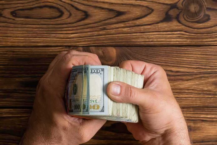 shutterstock_1089144368 Hands holding a thick stack of U.S. hundred-dollar bills