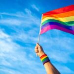 Turkey’s Night Raids – Rights Crackdown Sparks Brussels Fury Hand holding a rainbow pride flag against a blue sky