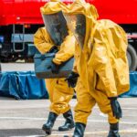 Washington Mill Chemical Disaster Kills Workers – Safety Failures Suspected Hazmat workers in yellow suits carry equipment near a tanker truck