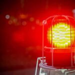 Red emergency warning light with protective cage glowing at night