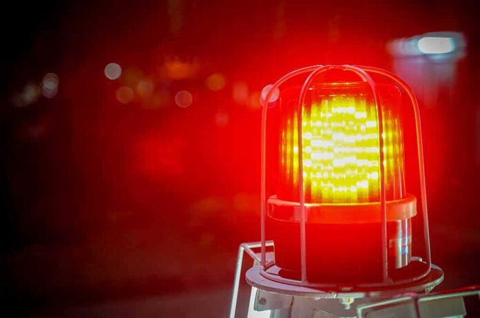 Red emergency warning light with protective cage glowing at night