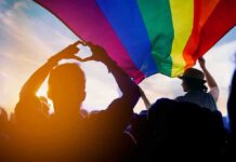 Pride-To-Swastika Image Explodes Online Crowd under a rainbow flag at sunset