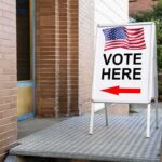 Election Police Banned? Oversight Cut Back Sidewalk sign with American flag directing to a polling place