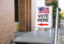 Election Police Banned? Oversight Cut Back Sidewalk sign with American flag directing to a polling place