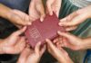 Multiple hands holding a red Bible