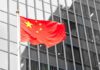 Supersonic Gamble: Beijing’s Year-End Push Chinese flag waving against glass office building