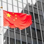 Supersonic Gamble: Beijing’s Year-End Push Chinese flag waving against glass office building
