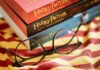 Round black glasses on striped scarf beside Harry Potter books