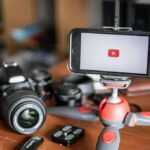 Influencers BANNED: Six Flags Drops HAMMER After Wild Stunt Smartphone on mini tripod beside DSLR camera and lenses
