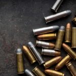 Shipping Meltdown: Bullets Land in Art Class Assorted handgun cartridges on a dark metal surface
