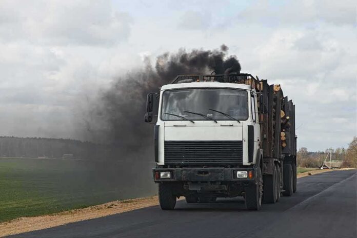 shutterstock_1715489095 Log truck emits black exhaust on rural road