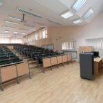 Empty lecture hall with tiered seating and a teacher's desk