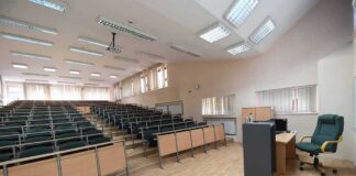 Empty lecture hall with tiered seating and a teacher's desk