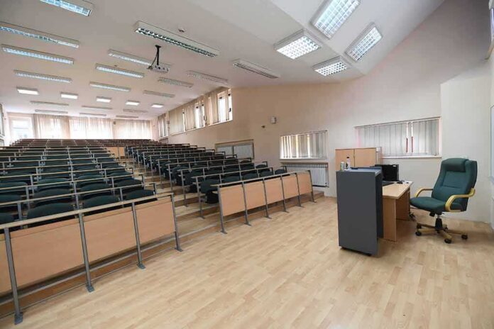 shutterstock_1804724047 Empty lecture hall with tiered seating and a teacher's desk