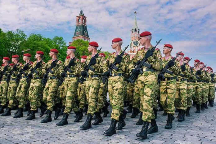 shutterstock_1934654819 Soldiers in camouflage uniforms march in formation with rifles