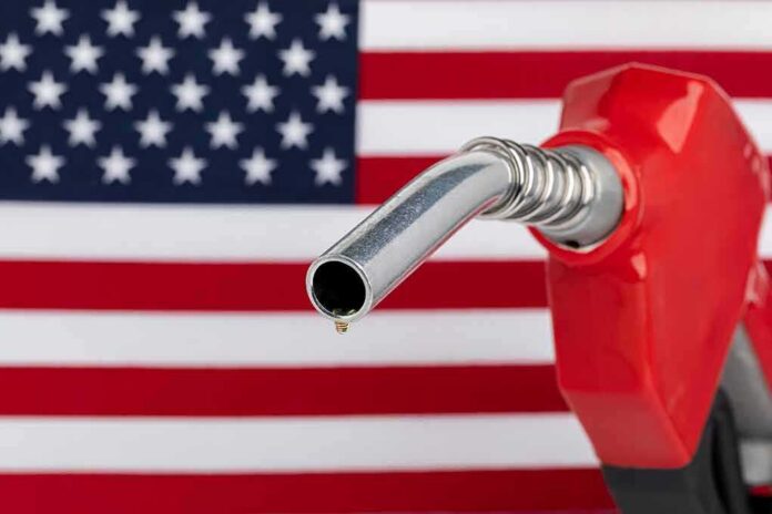 shutterstock_2133551549 gas pump nozzle with droplet against American flag background