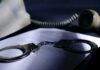 Phone Records Grabbed – Who Got Swept? Handcuffs on a document beside a coiled telephone handset