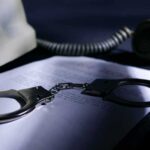 Phone Records Grabbed – Who Got Swept? Handcuffs on a document beside a coiled telephone handset