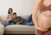 Ban Surrogacy Worldwide? Stakes Skyrocket Pregnant woman holding her belly in a living room